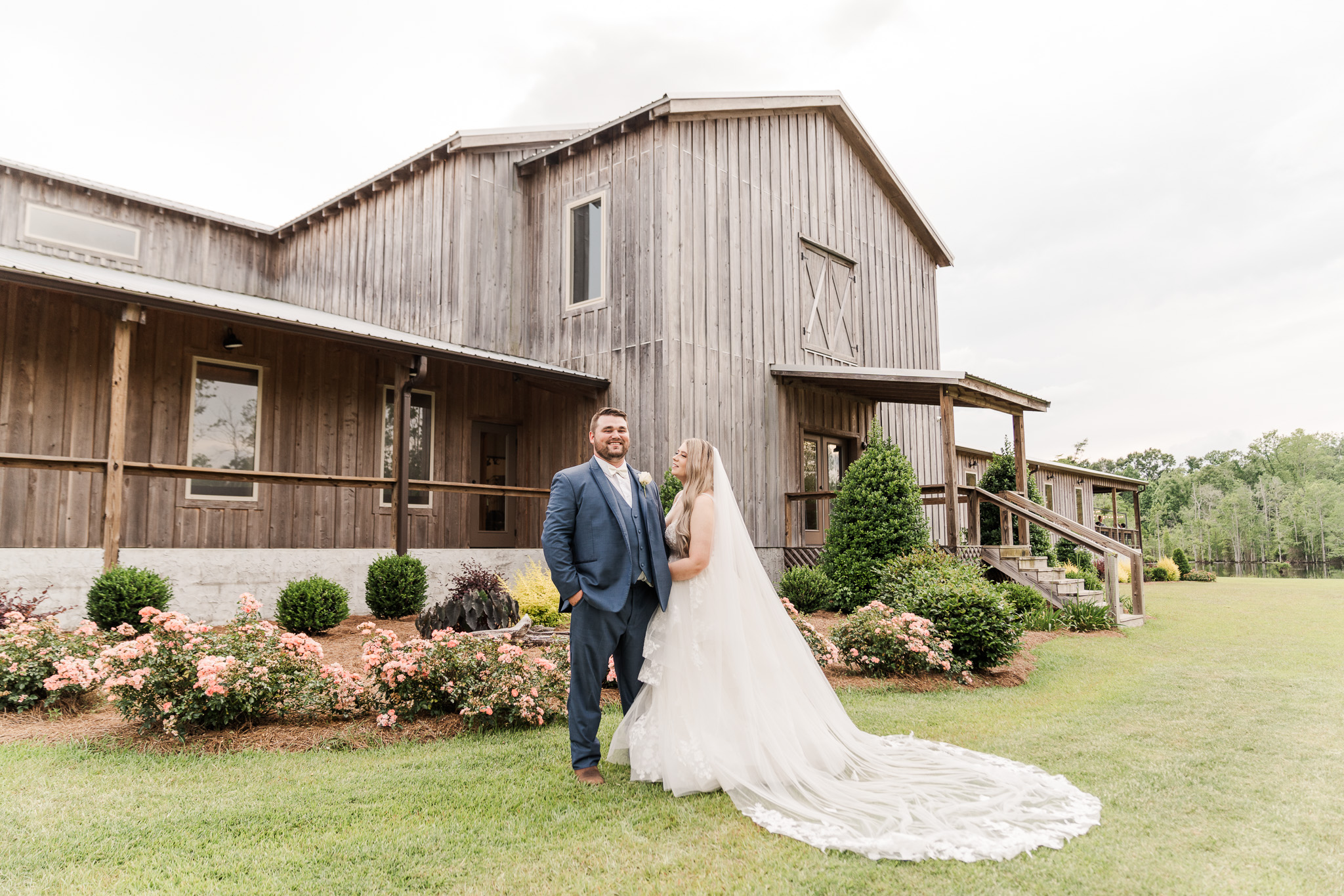 Bride and groom stand in front of barn at Magnolia Bay in Dothan, Alabama for their wedding video