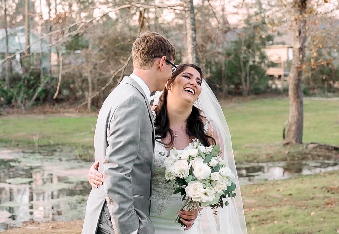 Bride smiles as her groom whispers in her ear for their wedding video at The Greystone in Mandeville, Louisiana