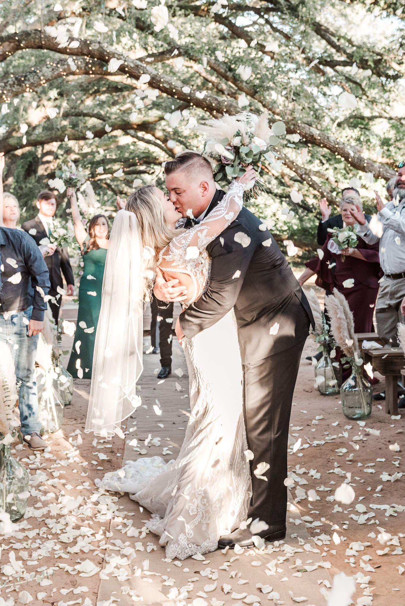 Bride and groom kiss in the aisle of their Oak Hollow Farm ceremony as their guests toss flower petals over them for their Fairhope wedding video.