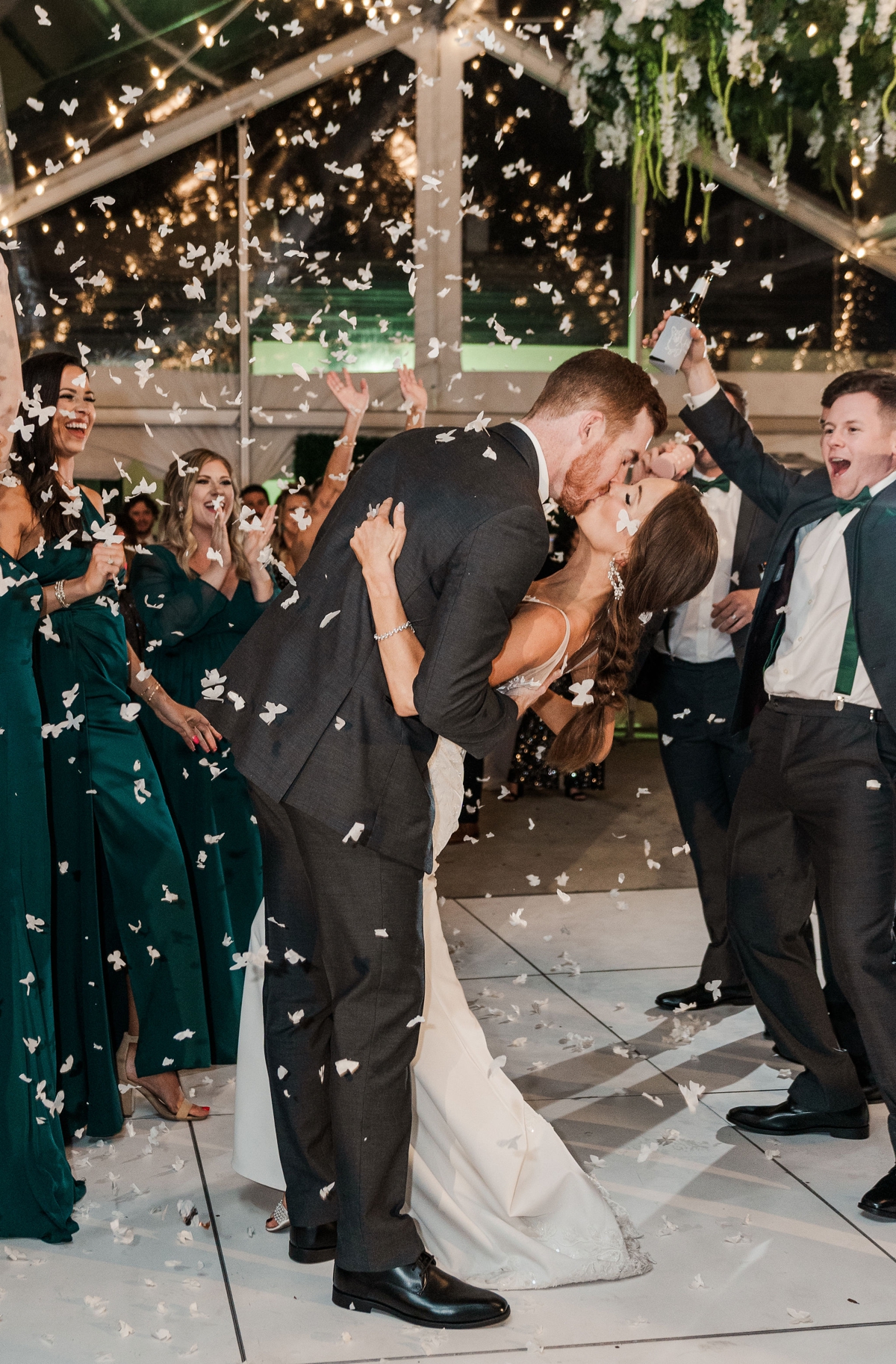 Bride and Groom celebrate by kissing through a tunnel of guests while confetti falls for their The Venue wedding