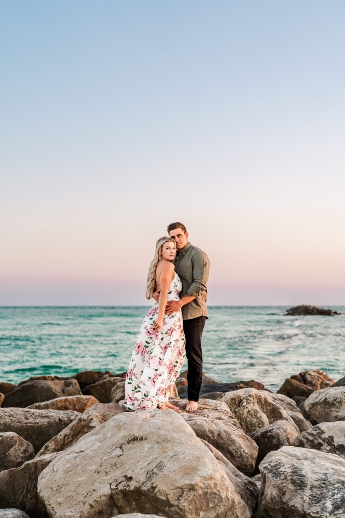 Engaged couple standing on jetty rocks at Alabama Point in Orange Beach, AL for their beach engagement photos