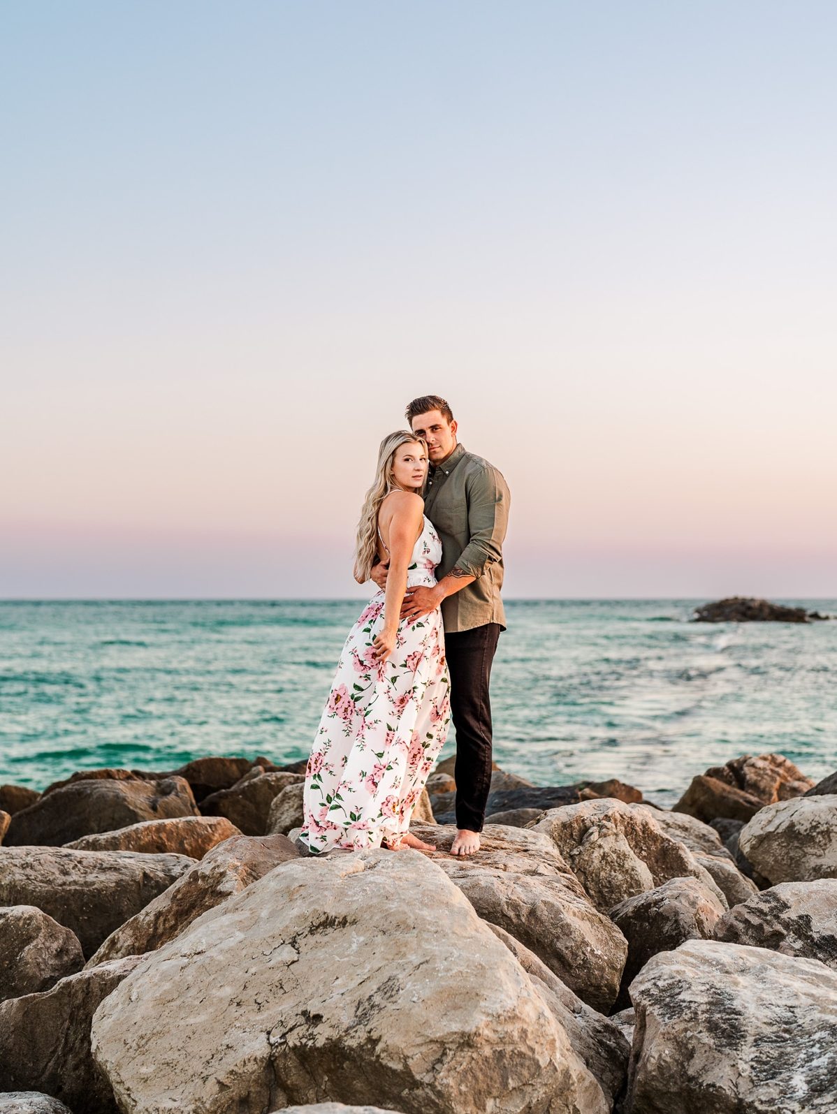 Engaged couple standing on jetty rocks at Alabama Point in Orange Beach, AL for their beach engagement photos