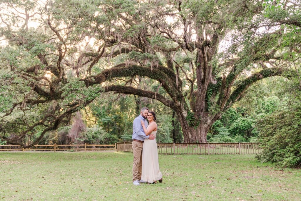 Man romantically holds woman while standing in a field for their Blakeley State Park engagement photos