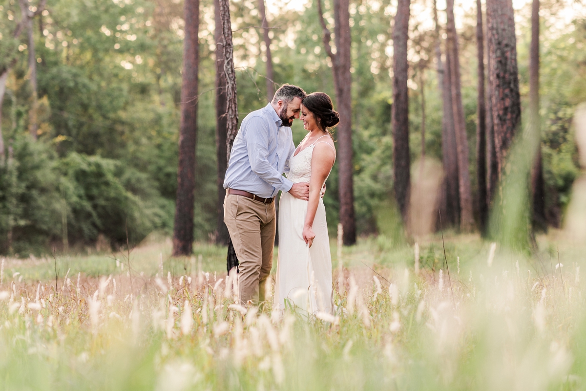 Man romantically holds woman while standing in a field for their Blakeley State Park engagement photos