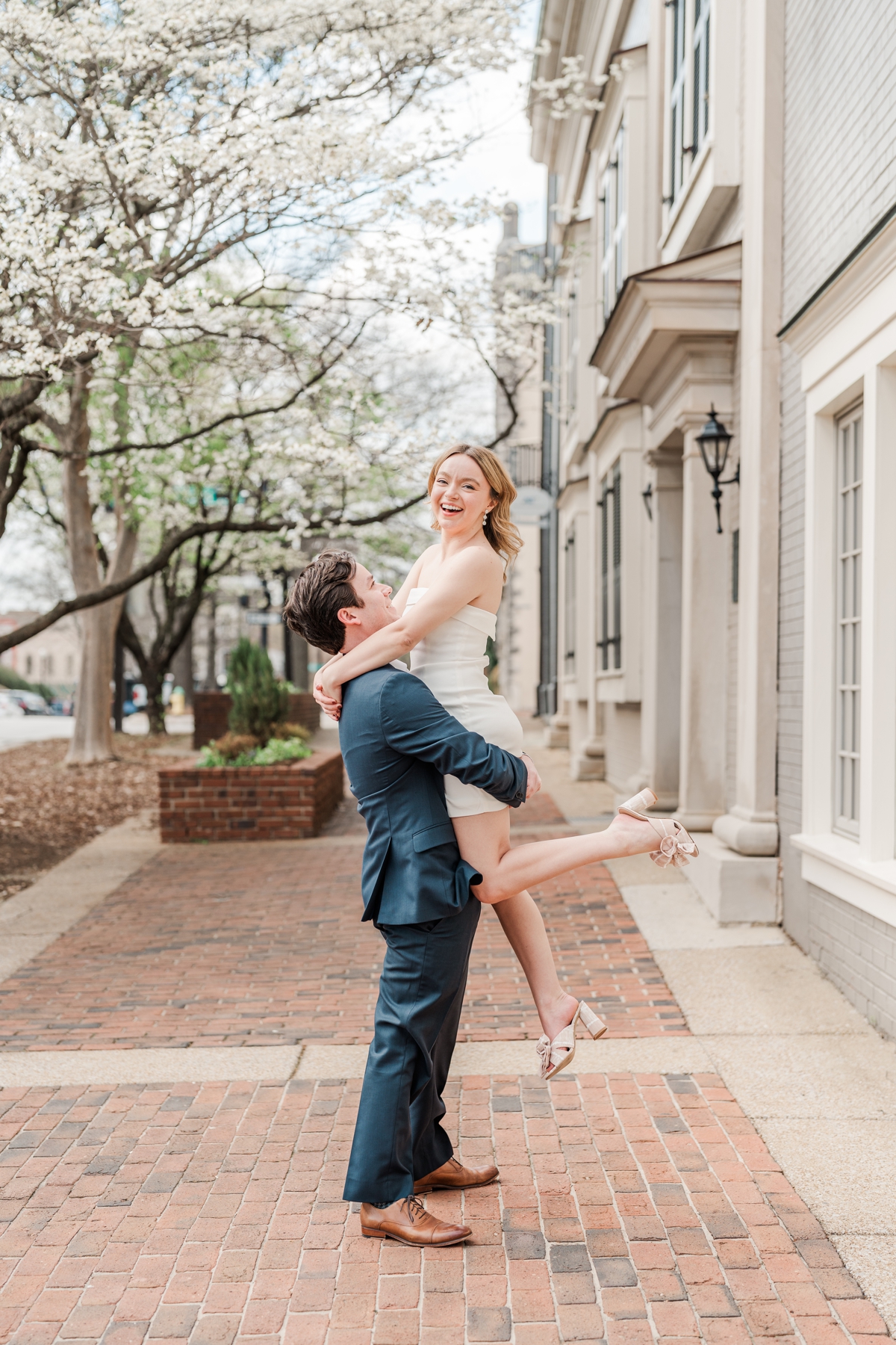 Man picks up woman while she smiles at the camera for their Huntsville, Alabama engagement shoot