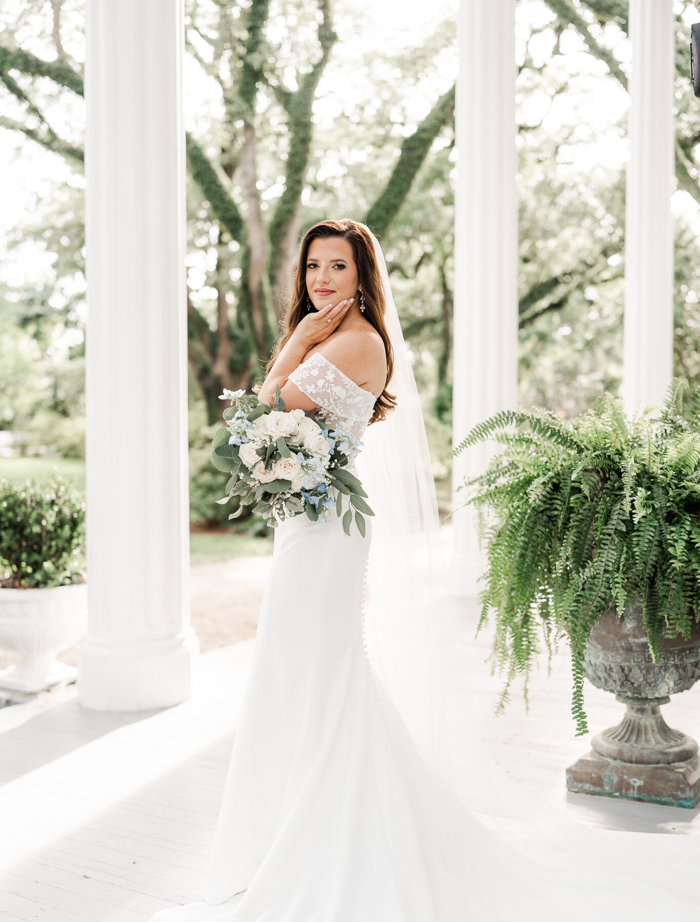 Amanda poses for her Bragg-Mitchell Mansion bridal photos on the front porch with large white columns in the background
