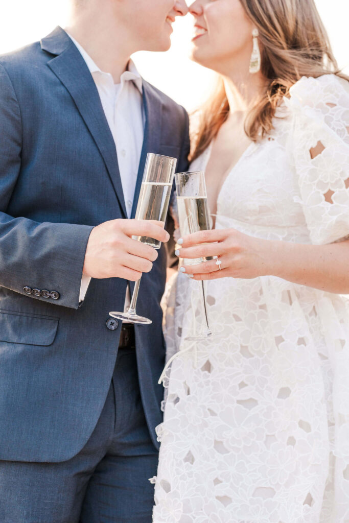 Man and woman hold champagne for their engagement photos and snuggle up while standing next to each other