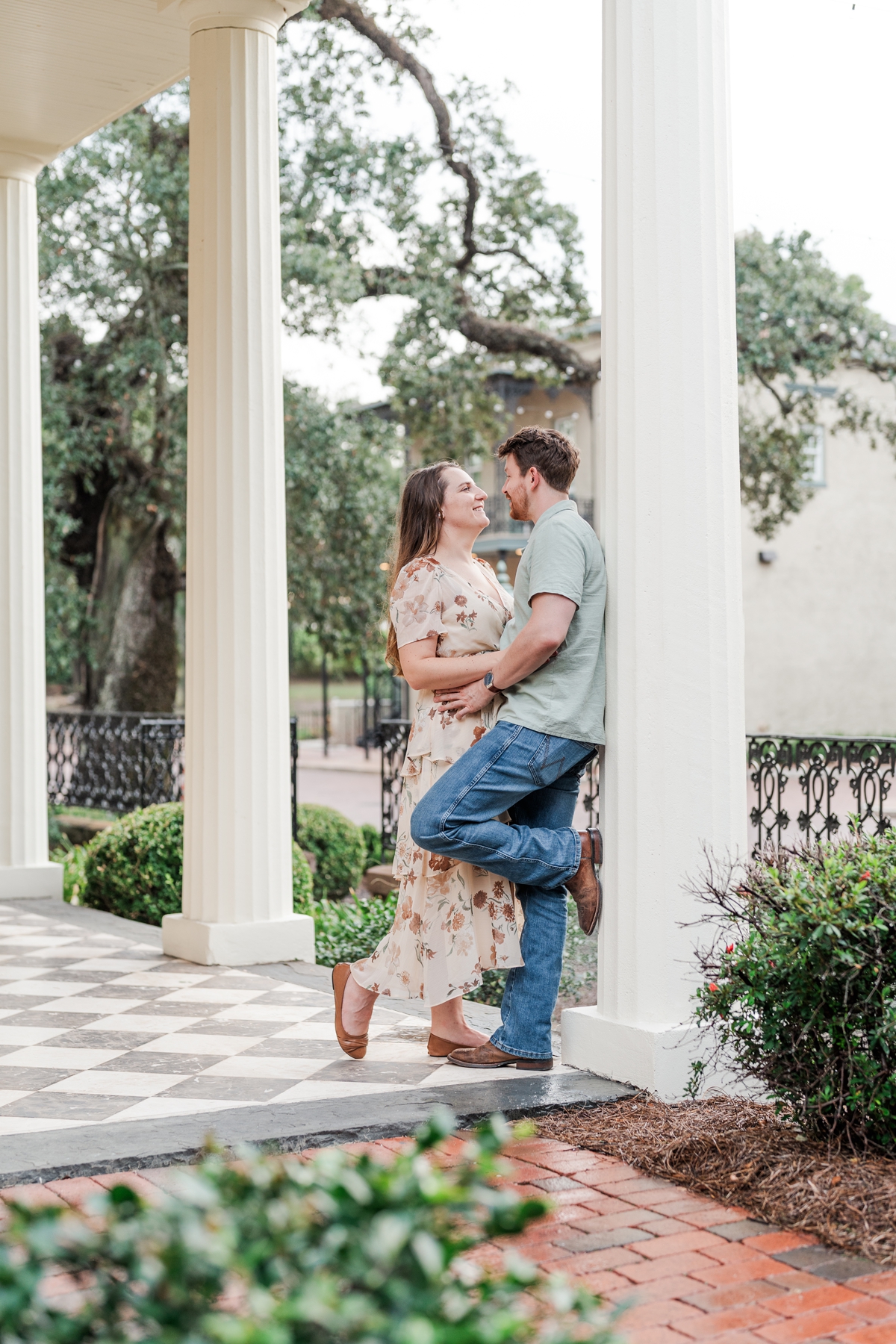 Man and woman lean against column at the historical Fort Conde Inn in Mobile, AL for their engagement photos