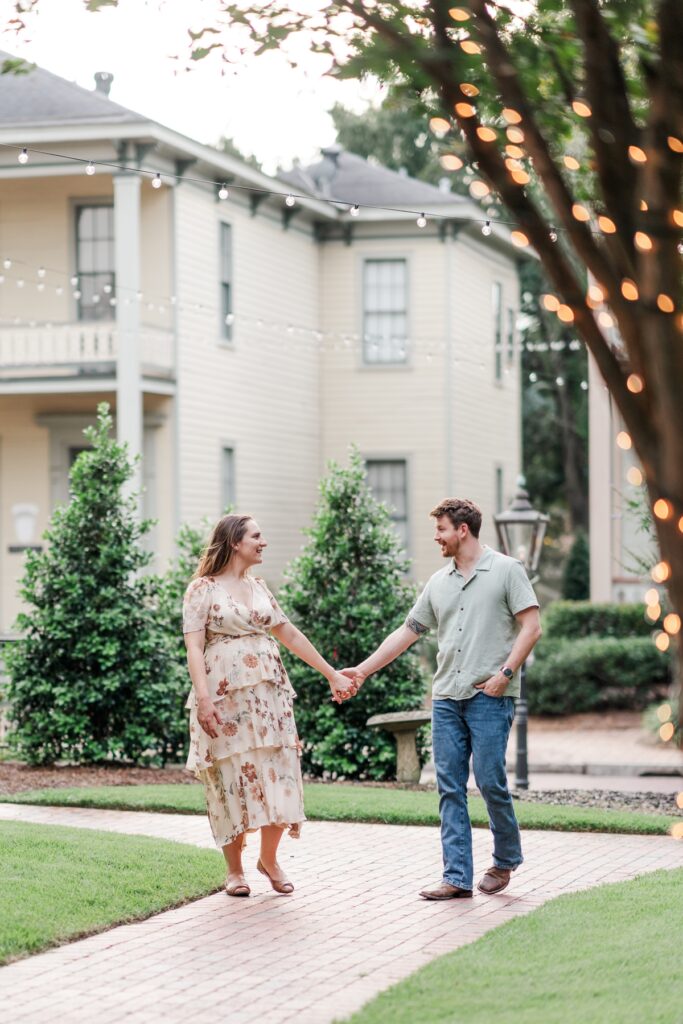 Man and woman walk on path at the historical Fort Conde Inn in Mobile, AL for their engagement photos
