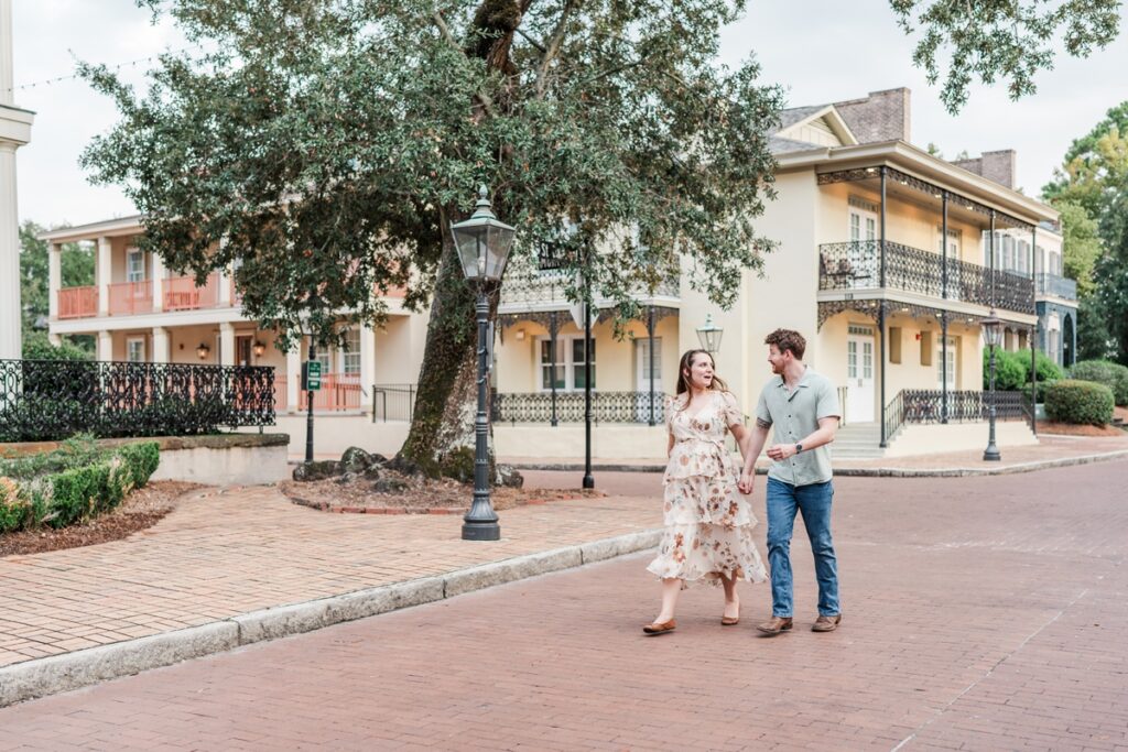 Man and woman walk on St. Emanuel Street at the historical Fort Conde Inn in Mobile, AL for their engagement photos