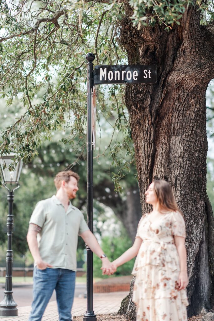 Man and woman stand in front of street sign